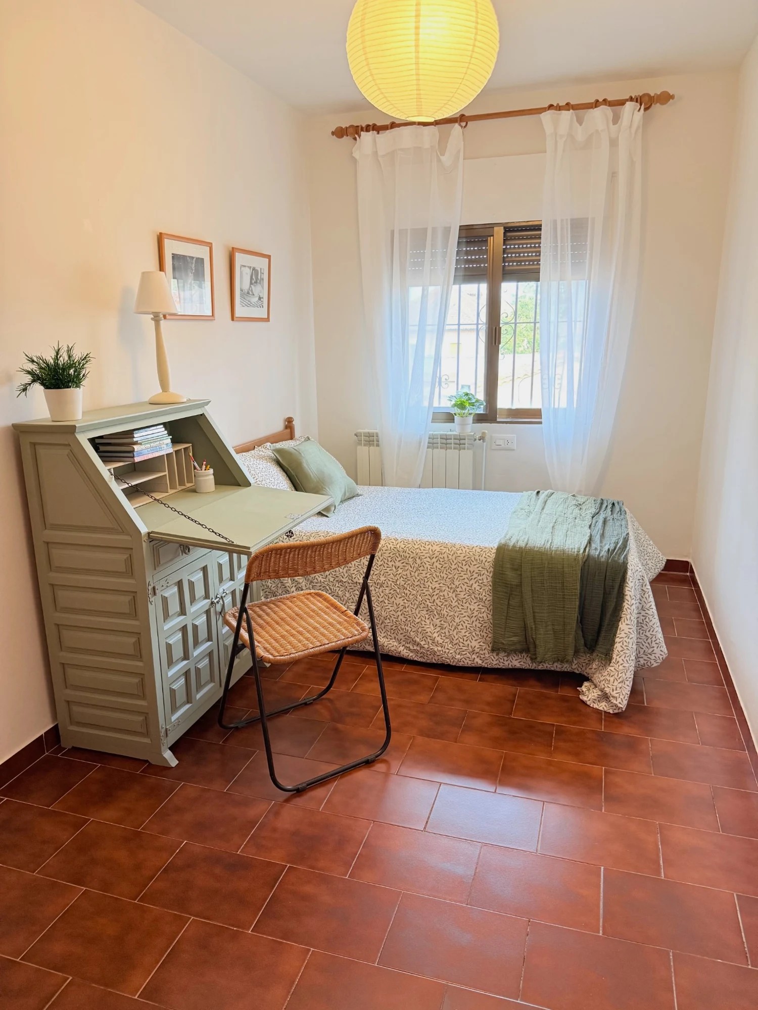 Después: cama vestida en blanco y verde, escritorio abatible, silla y lámpara de techo encendida